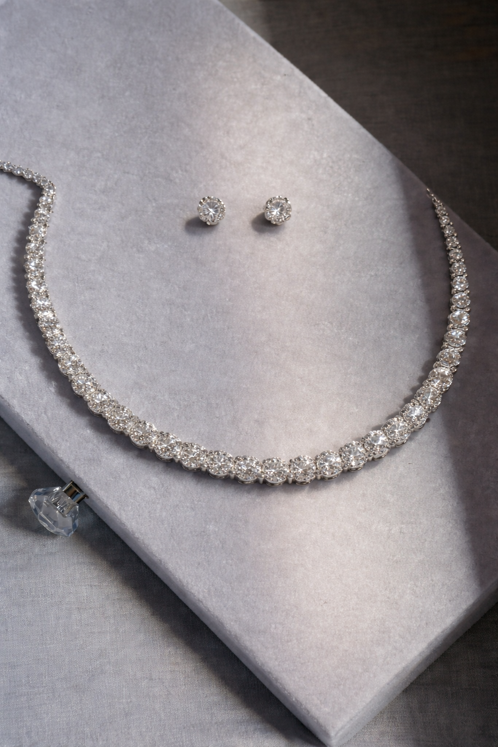 Silver necklace and earrings on a gray surface