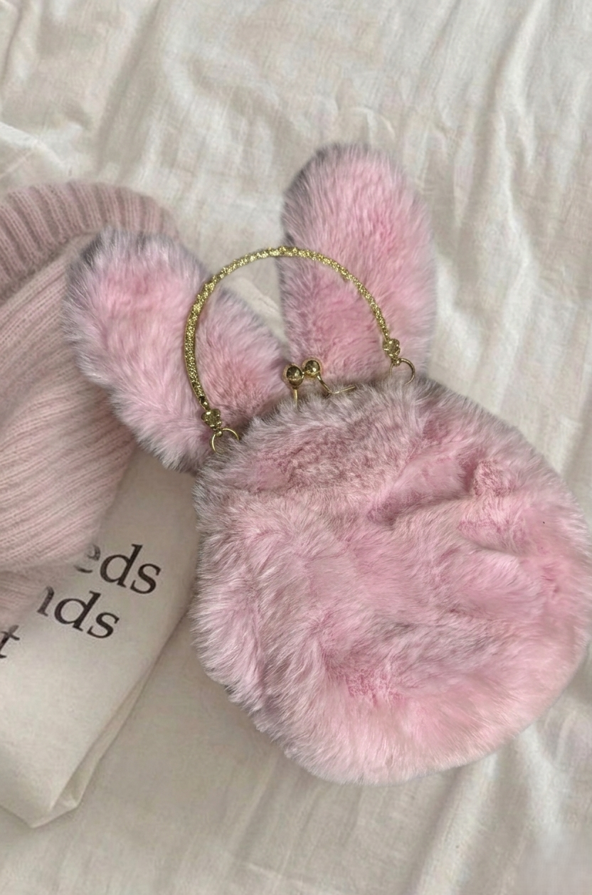 Pink fluffy handbag with bunny ears on a light fabric background