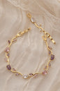 Gold bracelet with purple gemstones on a lace background