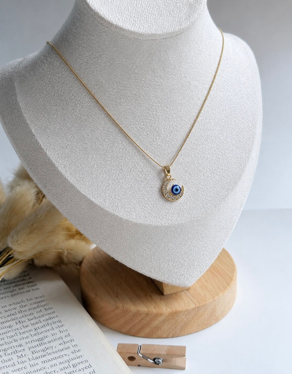 Gold necklace with an evil eye pendant on a white bust