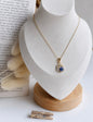 Necklace with an eye-shaped pendant on a white stand with a book in the background