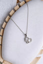 Heart-shaped necklace with a pearl pendant on a textured surface