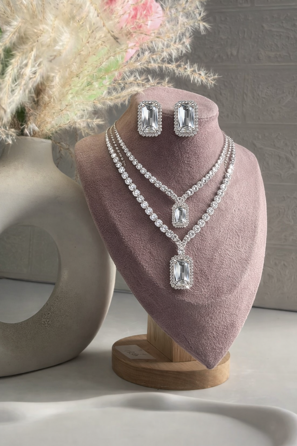 Jewelry set with necklace and earrings on a pink heart-shaped stand.