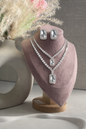 Jewelry set with necklace and earrings on a pink heart-shaped stand.