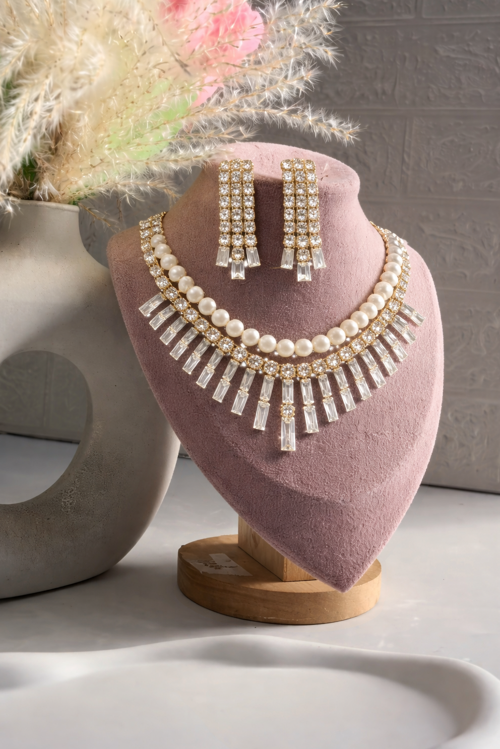 Pearl necklace and earrings on a pink stand with a blurred background