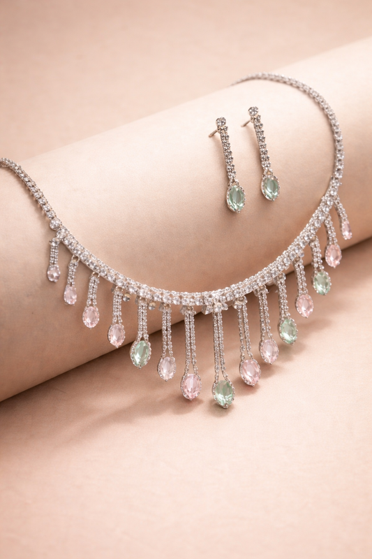 Necklace and earrings with teardrop-shaped gemstones on a soft pink background