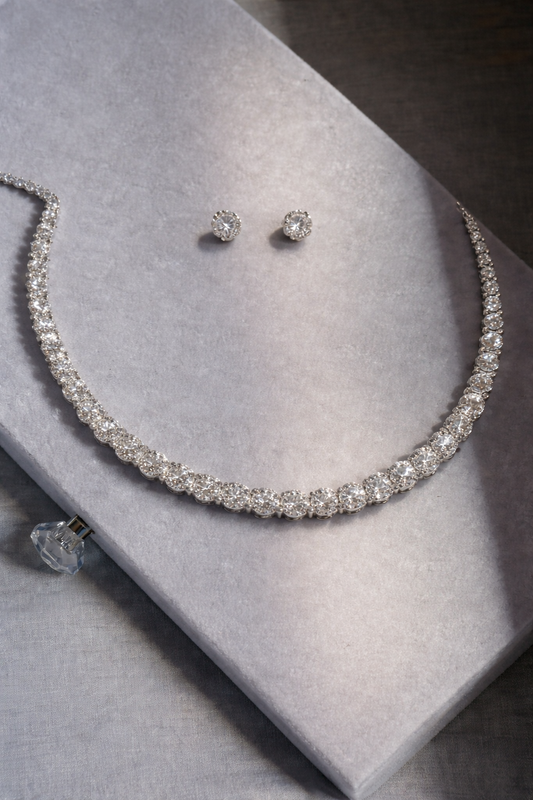 Silver necklace and earrings on a gray surface