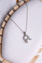 Silver necklace with a pendant featuring a pearl on a white surface.