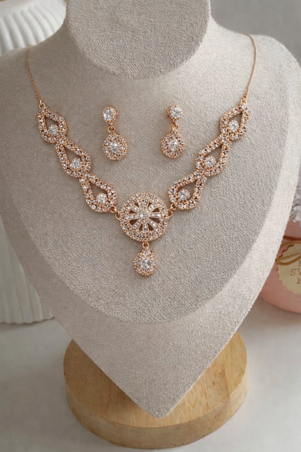 Rose gold necklace and earrings set on a mannequin bust.