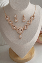 Rose gold necklace and earrings set on a mannequin bust.