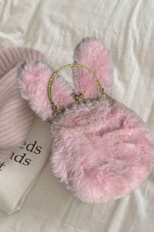 Pink fluffy handbag with bunny ears on a light fabric background