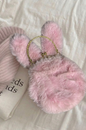 Pink fluffy handbag with bunny ears on a light fabric background