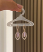 Rose gold earrings with pink gemstones on a clear hanger against a neutral background
